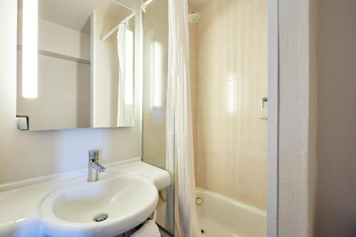 a white bathroom with a sink and a shower at B&B HOTEL Le Havre Harfleur 1 in Harfleur