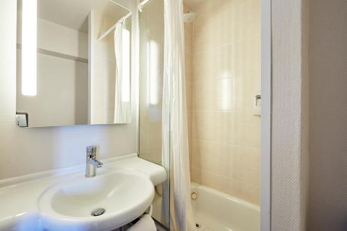 a white bathroom with a sink and a shower at B&B HOTEL Le Havre Harfleur 1 in Port de Harfleur