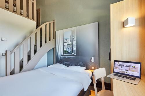 1 dormitorio con 2 camas y escritorio con ordenador portátil en B&B HOTEL Le Havre Harfleur 1, en Harfleur