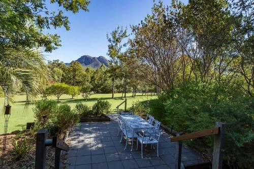 a patio with a table and chairs in a park at Tuckeroo Cottages & Gardens in Rathdowney