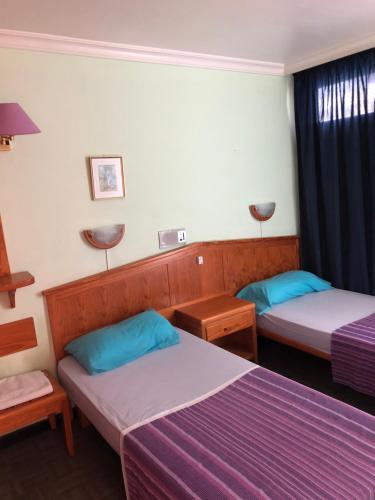 2 camas en una habitación con sábanas azules y moradas en Apartamentos Aloe, en Playa del Inglés