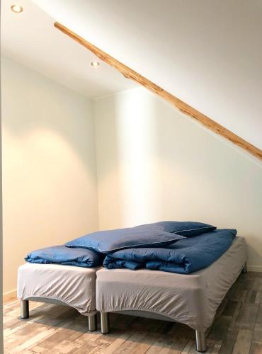 a bed with blue pillows on it in a room at Røst Bryggehotell in Røst