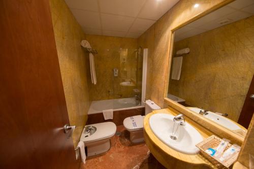 a bathroom with a sink and a toilet and a mirror at Hotel Aroi Bierzo Plaza in Ponferrada