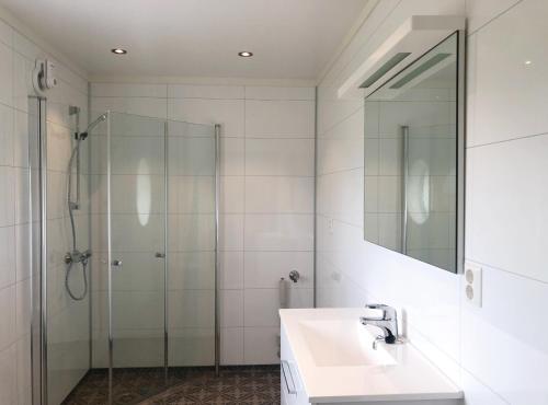 a bathroom with a shower and a sink and a mirror at Røst Bryggehotell in Røst