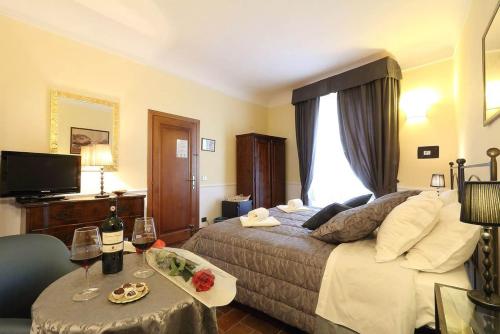 Habitación de hotel con cama y mesa con copas de vino en B&B Relais Il Campanile en Florencia