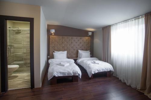 a hotel room with two beds and a shower at Garni Hotel Garson-Lux NS in Novi Sad