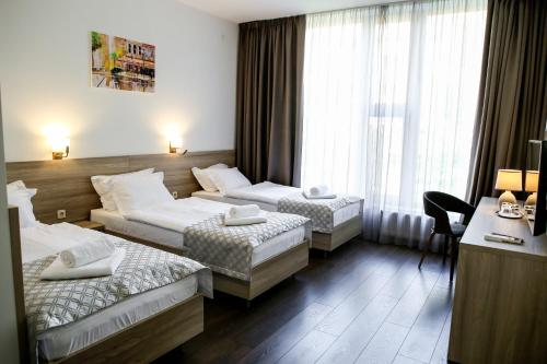 a hotel room with two beds and a desk at Hotel Antonio in Uzhhorod