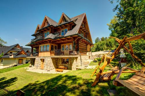 a large wooden house on top of a yard at Apartamenty Willa Olsza - wood house & mountain view in Zakopane