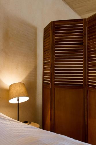 a bedroom with a bed and a lamp and a closet at Le Puy Carmin - Chambre d'hôtes avec jacuzzi in Bazoges-en-Paillers