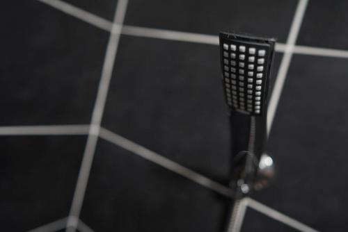 a black toothbrush hanging on a black tiled wall at Apartments & Dream Rooms in Niš