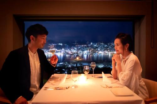 a man and woman sitting at a table with wine glasses at Garden Terrace Nagasaki Hotels & Resorts in Nagasaki