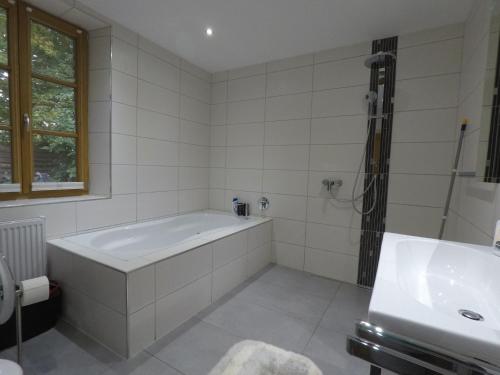 a white bathroom with a tub and a sink at Ferienwohnung auf dem Sturmhof in Grefrath