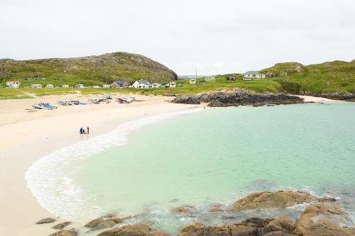 a beach with a group of people in the water at Achmelvich Beach Youth Hostel in Achmelvich