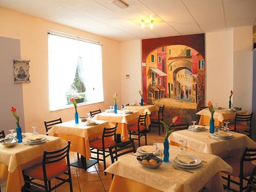 un restaurant avec des tables et des chaises et une peinture murale. dans l'établissement Hotel Adriana, à Laigueglia