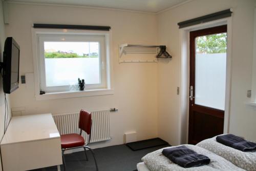 a room with two beds and a desk and a window at Nordic Inn Thorshavn in Tórshavn