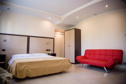 a bedroom with a bed and a red chair at Hotel Citta' Di Conegliano in Conegliano