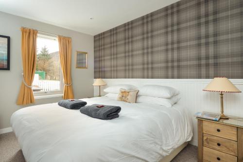 a bedroom with a white bed with two towels on it at Highland Holiday Cottages in Newtonmore