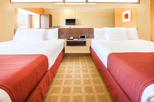 a hotel room with two beds and a tv at Microtel Inn by Wyndham Stillwater in Stillwater