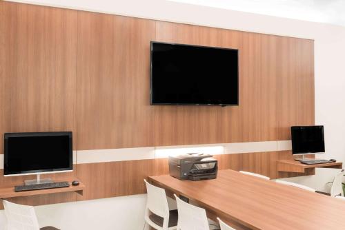 a room with a desk with a computer and a television at Microtel Inn & Suites by Wyndham Binghamton in Binghamton
