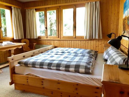 um quarto com uma cama num quarto com janelas em Alpenchalet Trutmundi undri em Eischoll