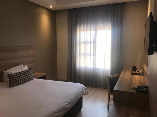 a hotel room with a bed and a window at Regal Inn Hotel Midrand in Midrand