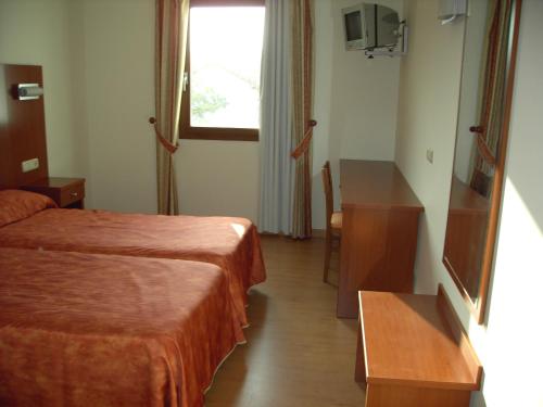 a hotel room with two beds and a desk at Hotel Agorreta in Salinas de Pamplona