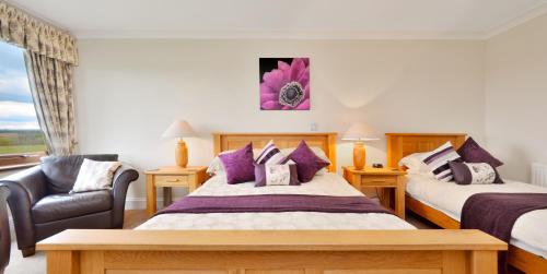 a hotel room with two beds and a chair at Peggyslea Farm B&B in Edinburgh