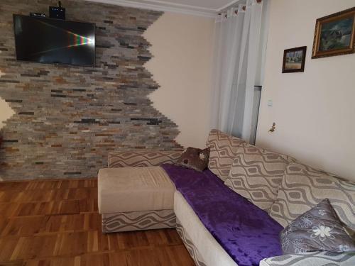Una sala de estar con un sofá y una pared de ladrillos. en Apartman Cici, en Zlatibor