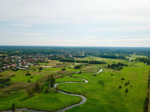 an aerial view of a green field with a river at Bliżej Natury in Białowieża