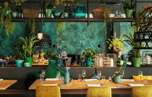 a restaurant with wooden tables and chairs and plants at Van der Valk Hotel Stein Urmond in Urmond