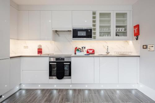 a white kitchen with white cabinets and a black appliance at Roomspace Serviced Apartments - The Legacy in Brighton & Hove