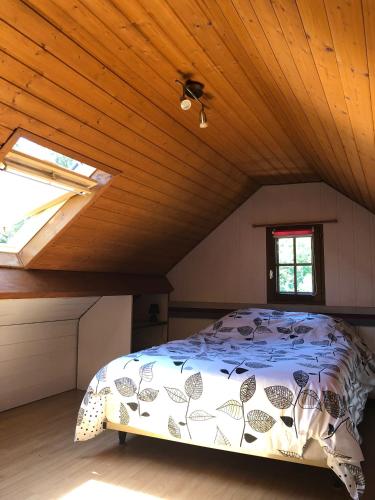 une chambre avec un lit dans un grenier dans l'établissement Aux lettres du lavoir, à La Rivière-Saint-Sauveur