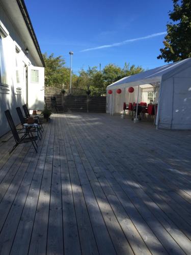 a wooden deck with chairs and a tent at Norrgården i Sandviken in Sandviken