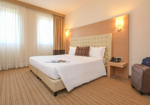 a hotel room with a large bed and a suitcase at TH Lazise - Hotel Parchi Del Garda in Lazise