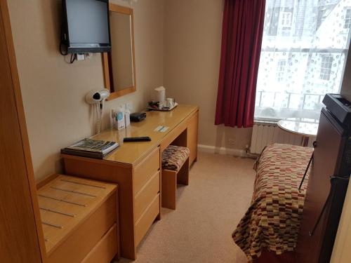 a bedroom with a desk and a television at Best Western Moores Central Hotel in St. Peter Port