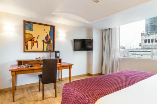 a hotel room with a desk and a bed and a window at Eurostars Zona Rosa Suites in Mexico City