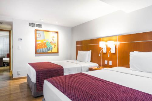 a hotel room with two beds and a desk at Eurostars Zona Rosa Suites in Mexico City