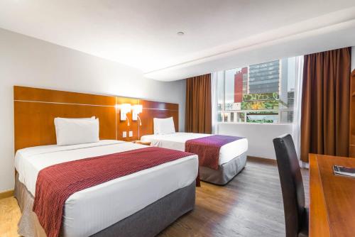 a hotel room with two beds and a window at Eurostars Zona Rosa Suites in Mexico City