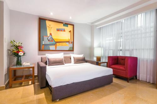 a bedroom with a bed and a red chair at Eurostars Zona Rosa Suites in Mexico City