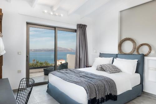 a bedroom with a bed with a view of the ocean at NiMar Villas in Plaka