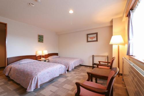 a hotel room with two beds and a table and chairs at Hotel Shirakabaso Shigakogen in Yamanouchi