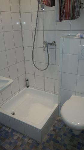 バート・カールスハーフェンにあるAktiv-Pensionの白いタイル張りのバスルーム(シャワー、トイレ付)