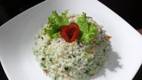 a white plate with rice and lettuce and tomato at Nature's Hideout Holiday Home in Mirigama
