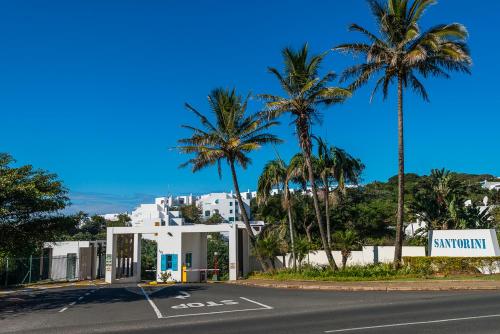 a street with palm trees and a white building at Santorini - Perissa 3 in Ballito