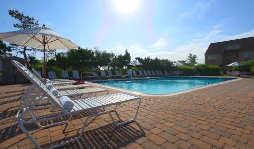 a swimming pool with lounge chairs and an umbrella at Windward Shores in Amagansett