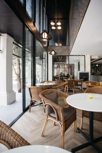 a restaurant with tables and chairs and windows at Diamond Park Inn Chiangrai & Resort in Chiang Rai