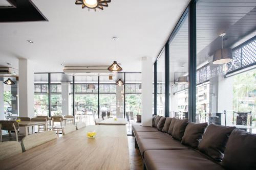 a large room with a couch and tables and windows at Diamond Park Inn Chiangrai & Resort in Chiang Rai
