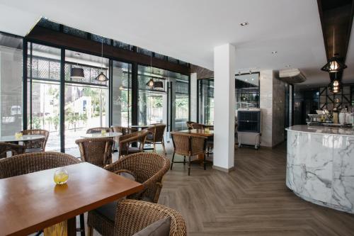a restaurant with tables and chairs and windows at Diamond Park Inn Chiangrai & Resort in Chiang Rai