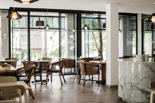 a restaurant with tables and chairs and windows at Diamond Park Inn Chiangrai & Resort in Chiang Rai