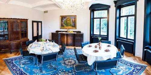 a dining room with two tables and chairs and a chandelier at Vila Olga in Jevany